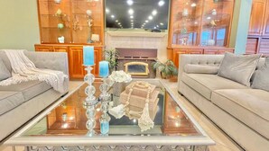 A modern living room with two sofas, a glass coffee table, and a fireplace. - Stunning Panoramic Waterfront Pool Home Escape (Anaheim)