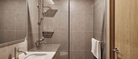 Un baño moderno con cabina de ducha de vidrio, lavamanos y perchero.