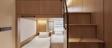 A compact, modern hotel room with two single beds, a small desk, and a built-in wardrobe.