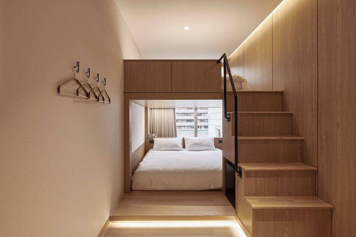 A bedroom with a bed, wooden wardrobe, and a staircase.