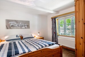 Une chambre à coucher avec un lit, une table de chevet avec une lampe, une fenêtre avec des rideaux et un mur orné d’un panneau indiquant « Détendez-vous ».