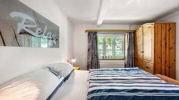 Ein Schlafzimmer mit einem Bett, einem Holzschrank, einem Fenster mit Vorhängen und einem an der Wand befestigten Schild.