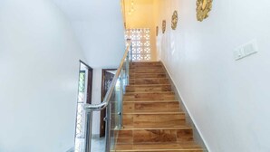 Eine Treppe mit Holzsufen und einem Glasgeländer, die zu einer Tür mit einem verzierten Gitterwerk führt.