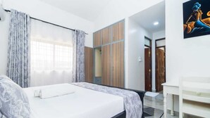 Ein modernes Hotelzimmer mit einem großen Bett, einem Kleiderschrank, einem Schreibtisch und einem Bild an der Wand.