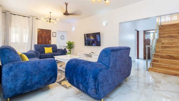 Ein modernes Wohnzimmer mit blauen Sofas, einem Couchtisch und einem an der Wand befestigten Fernseher.
