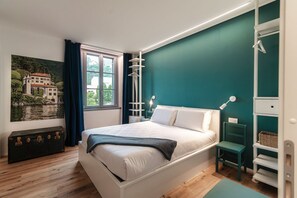 Un dormitorio con cama, ventana, un cuadro, cómoda y una silla.