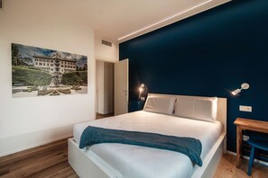 A bedroom with a bed, a nightstand, a desk, and a wall-mounted lamp. - Just in Front - MyHomeinComo (Cernobbio)