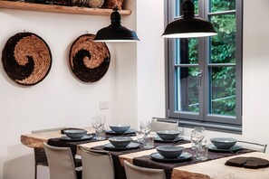 A dining area with a wooden table set for four, black plates, and a black pendant light. - Just in Front - MyHomeinComo (Cernobbio)