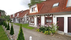 A row of traditional half-timbered houses with a cobblestone path and neatly trimmed hedges. - Apartment 'Ferienpark Gustow B09' with Shared Terrace and Shared Garden (Gustow)
