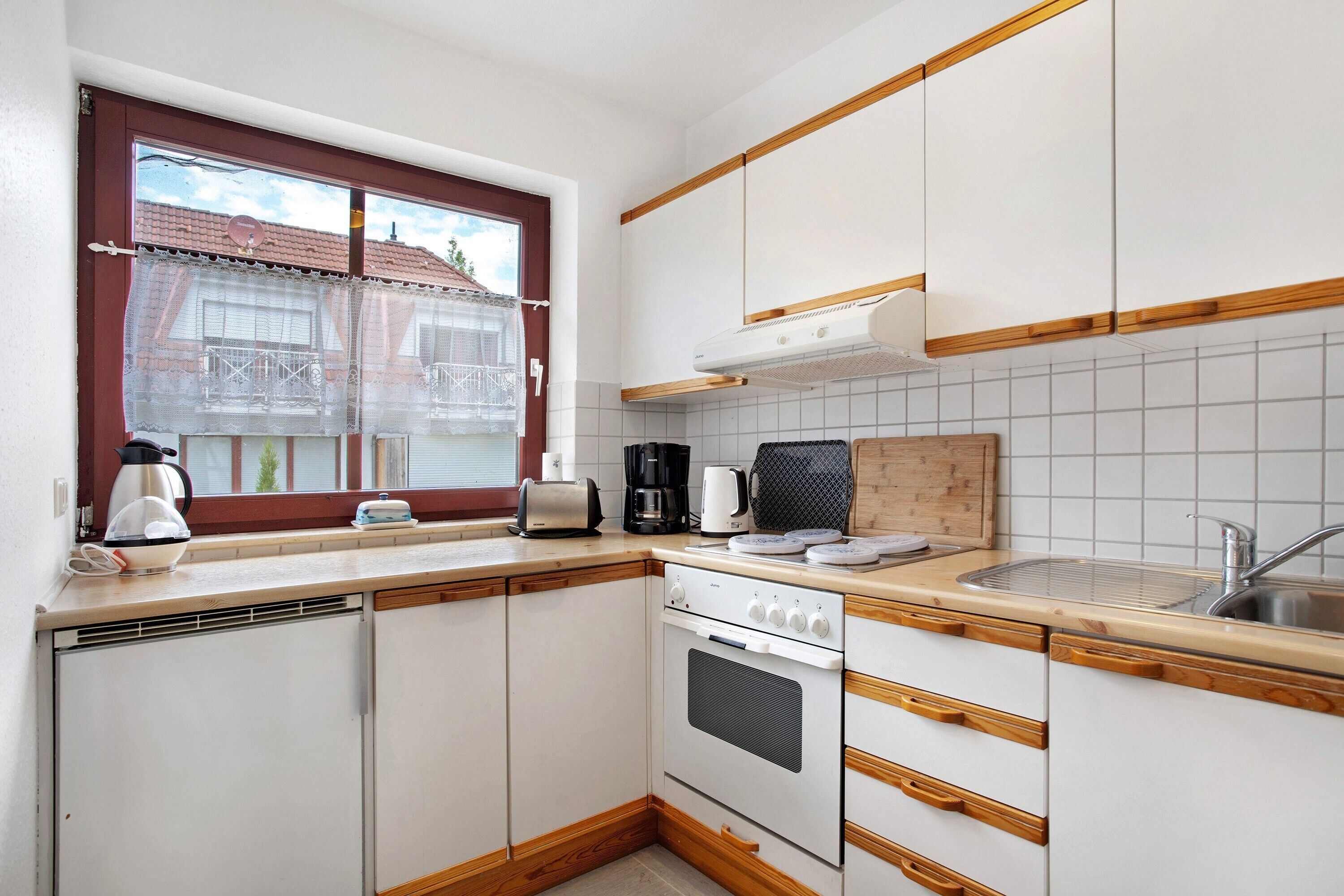 A compact kitchen with a window, a built-in oven, and a sink.