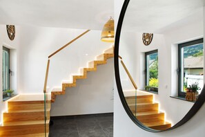 A modern staircase with wooden steps and glass railings, leading to a landing with a view of greenery outside. - Chalet 'Sonnenwald' with Mountain View, Balcony and Wi-Fi (Grattersdorf)
