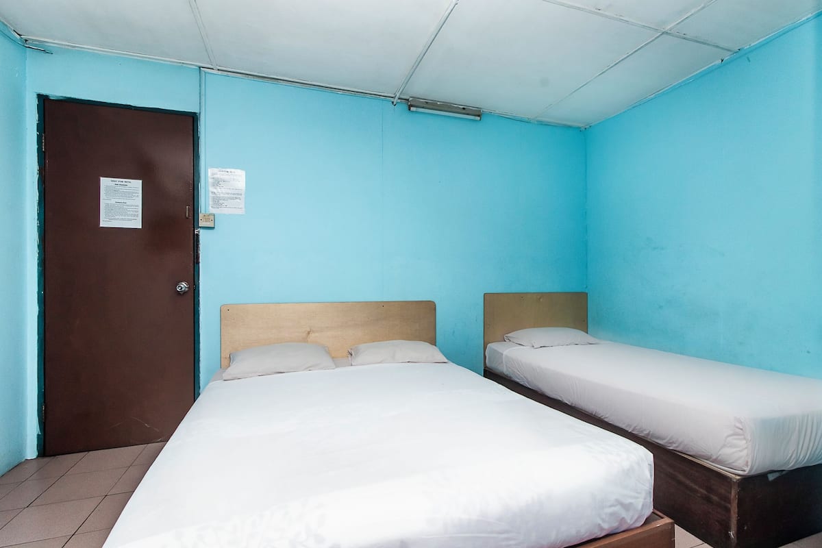 Une chambre avec deux lits, une porte et un ventilateur de plafond.