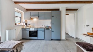 Une cuisine moderne avec des armoires grises, un four encastré et une poutre en bois au plafond.