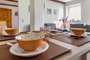 Una zona de comedor con dos platos de comida sobre una mesa, un vaso de agua y un armario de madera al fondo.