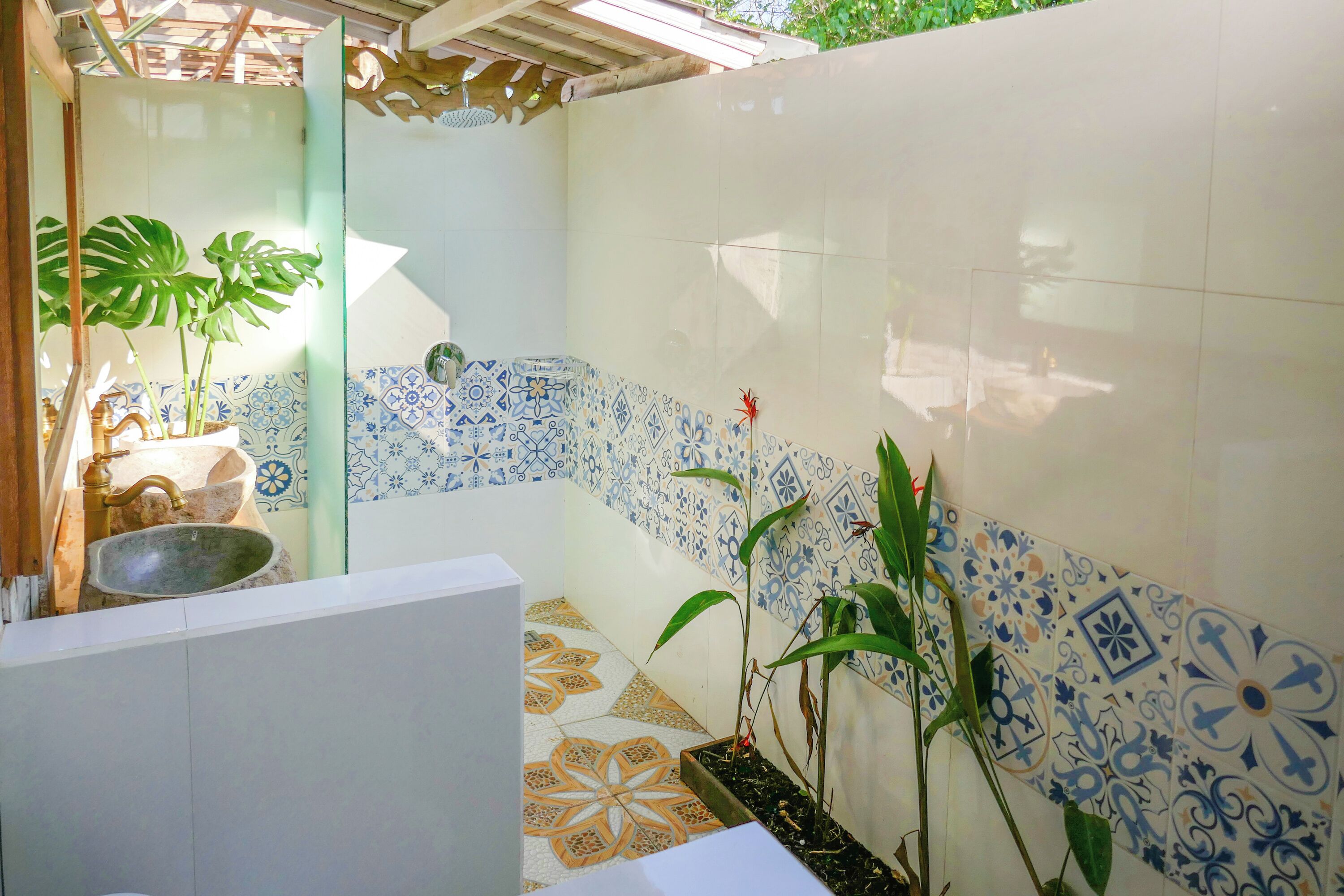 Casa de banho com lavatório, espelho e azulejos estampados.