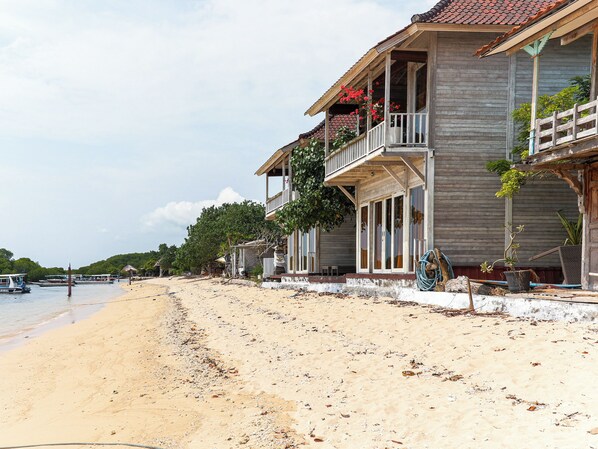 Une propriété située en bord de mer, avec un bâtiment en bois doté de balcons et d’une véranda couverte.