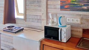 Une petite cuisine équipée d’un four à micro-ondes, d’une machine à café et d’une petite cuisinière.