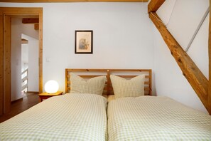 Ein Schlafzimmer mit zwei Betten, einem Holzkopfende, einer Nachttischlampe und einem gerahmten Bild an der Wand.