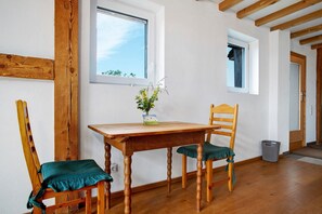 Una stanza con travi in legno, un tavolo di legno, due sedie, una finestra e una porta.