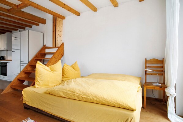 Une chambre à coucher avec un lit, une chaise, un bureau et un escalier.