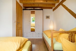 A bedroom with two beds, a wardrobe, and a window.