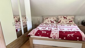 Un dormitorio con cama, armario, mesita de noche, lámpara y espejo.