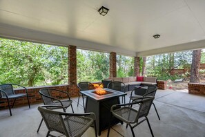 En udendørs patio med bålsted, siddepladser og murstenssøjler.