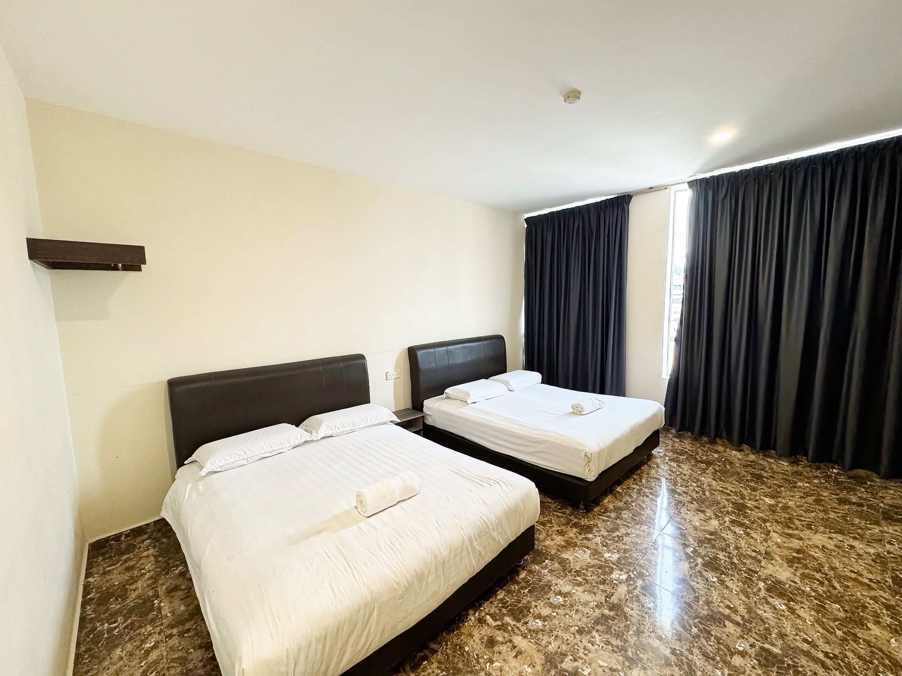 A hotel room with two beds, a marble floor, and a large window with curtains.