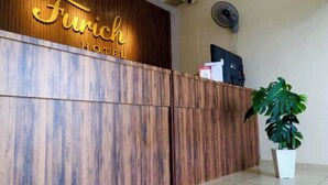En receptionsdisk med en träpaneldesign och namnet ”Firich Hotel” skrivet med guldfärg.