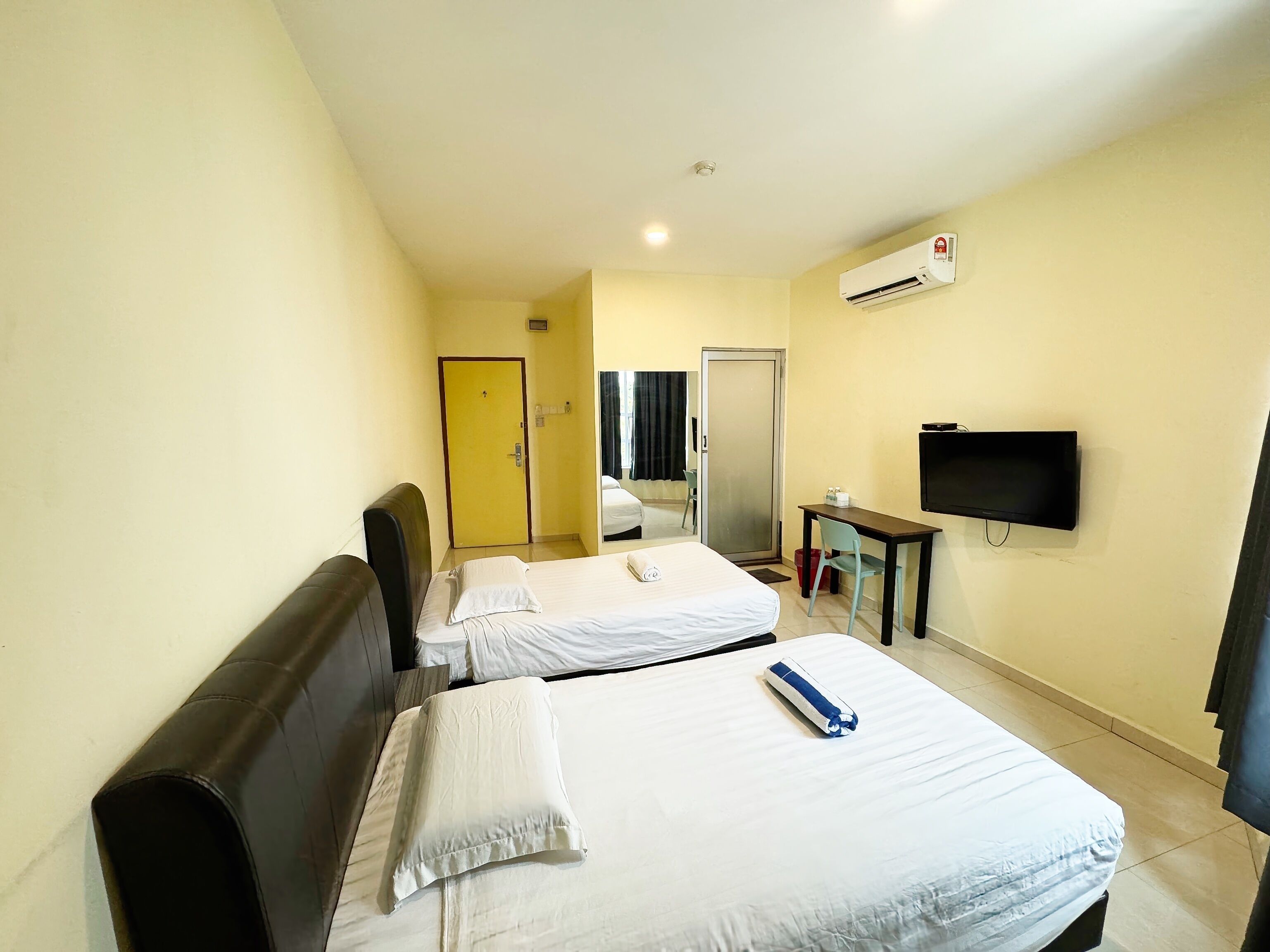 Une chambre d’hôtel avec deux lits, une télévision et un appareil de climatisation.
