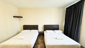 Una habitación de hotel con dos camas individuales, un estante pequeño, suelo de mármol y una cortina oscura.