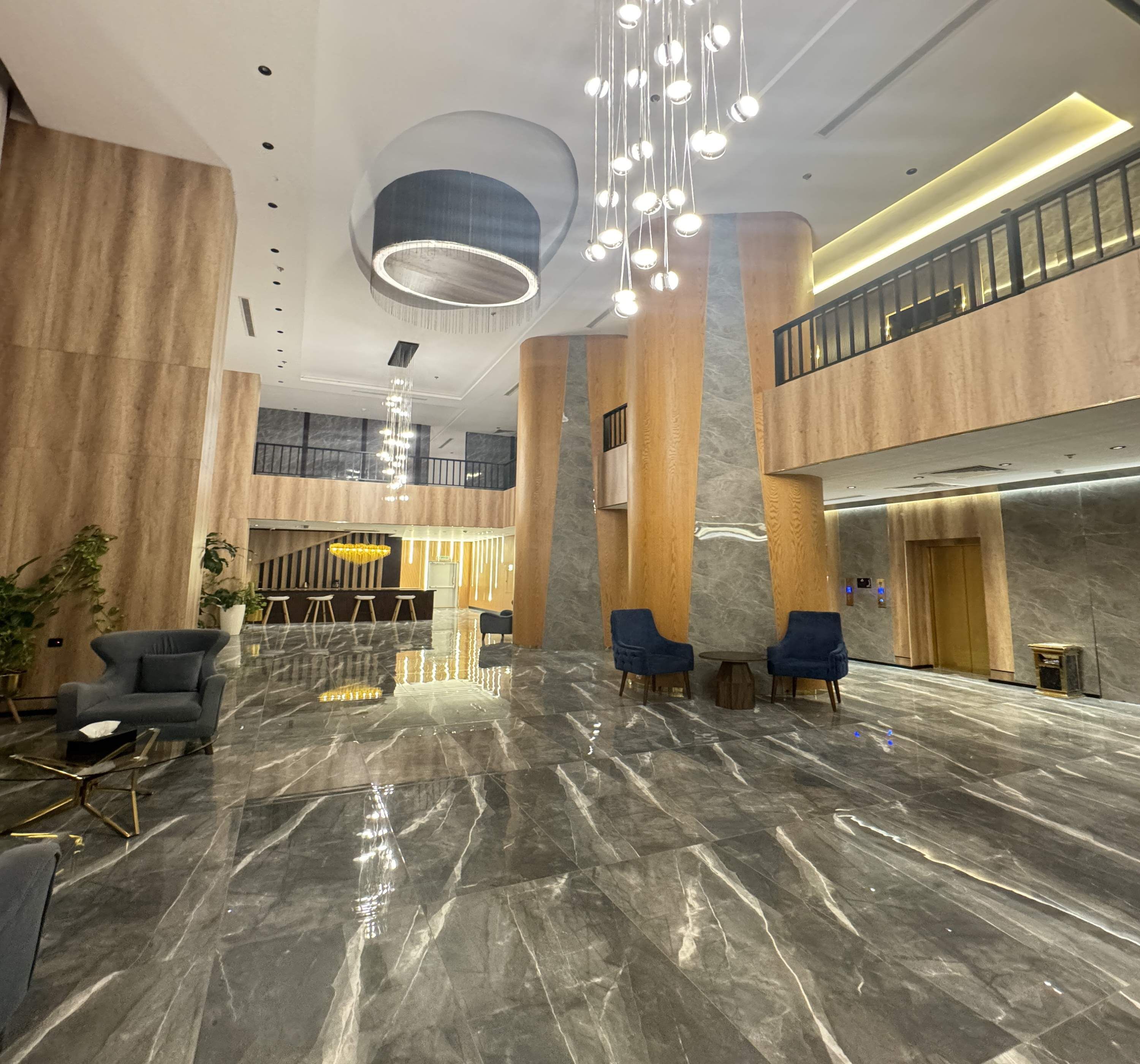 A spacious lobby with a marble floor, modern furniture, and a mezzanine level.
