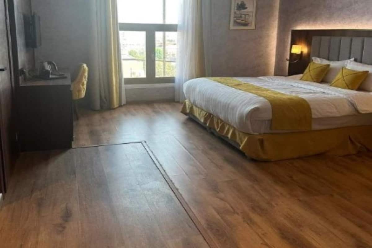 A hotel room with a bed, a desk, and a window.