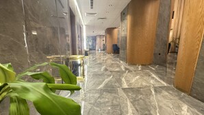 Un amplio pasillo con suelo de mármol, detalles de madera y una planta en maceta.