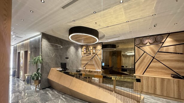 Un área de recepción moderna con piso de mármol, un mostrador curvo y un espejo grande.