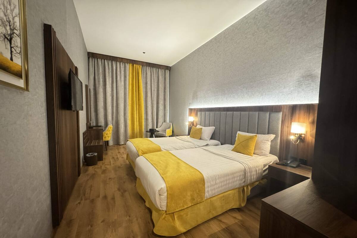 A hotel room with two beds, a TV, a desk, and a chair.
