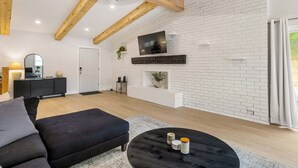 A modern living room with a black sofa, a round coffee table, and a white brick wall.