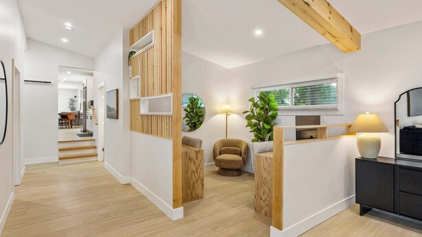 A modern interior with a wooden accent wall, a sofa, a lamp, and a TV on a cabinet.