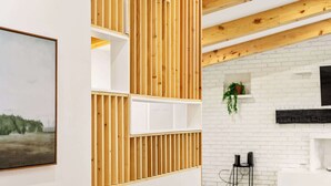 A modern interior with wooden slats, white brick walls, and a fireplace.