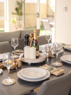 A dining table set with plates, glasses, a bottle of champagne, and candles.