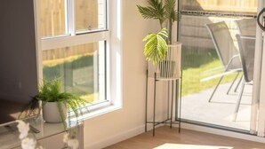 A modern living room with a large window, a sofa, a coffee table, and a potted plant. - Modern Family Retreat in Premier GreenbankLocation (Greenbank)