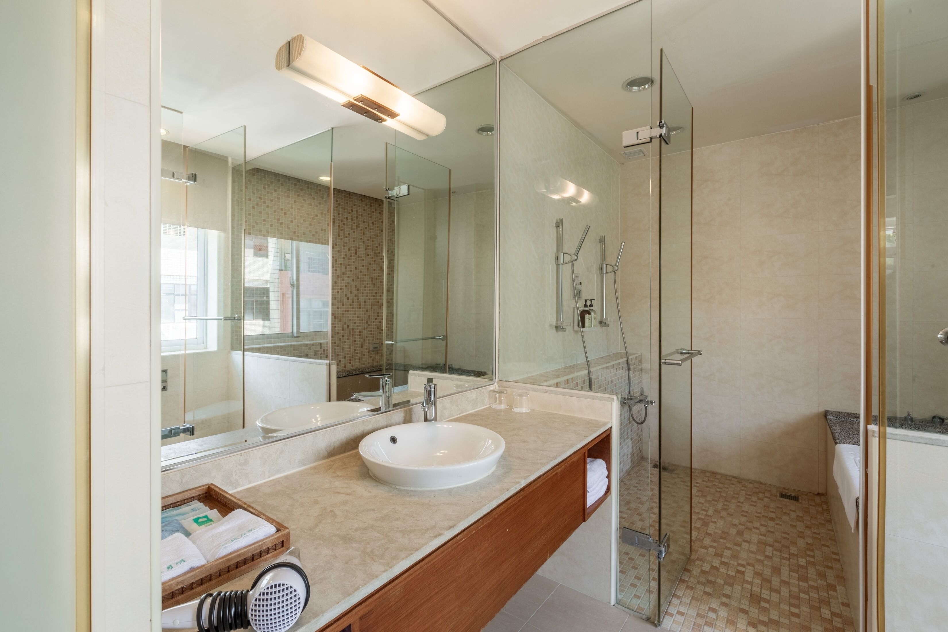 A modern bathroom with a large mirror, a sink, and a shower area.