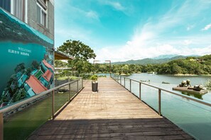 Une jetée en bois s’étendant au-dessus d’une étendue d’eau, ornée d’une fresque murale pittoresque, dotée d’une rambarde et offrant une vue sur le paysage environnant.