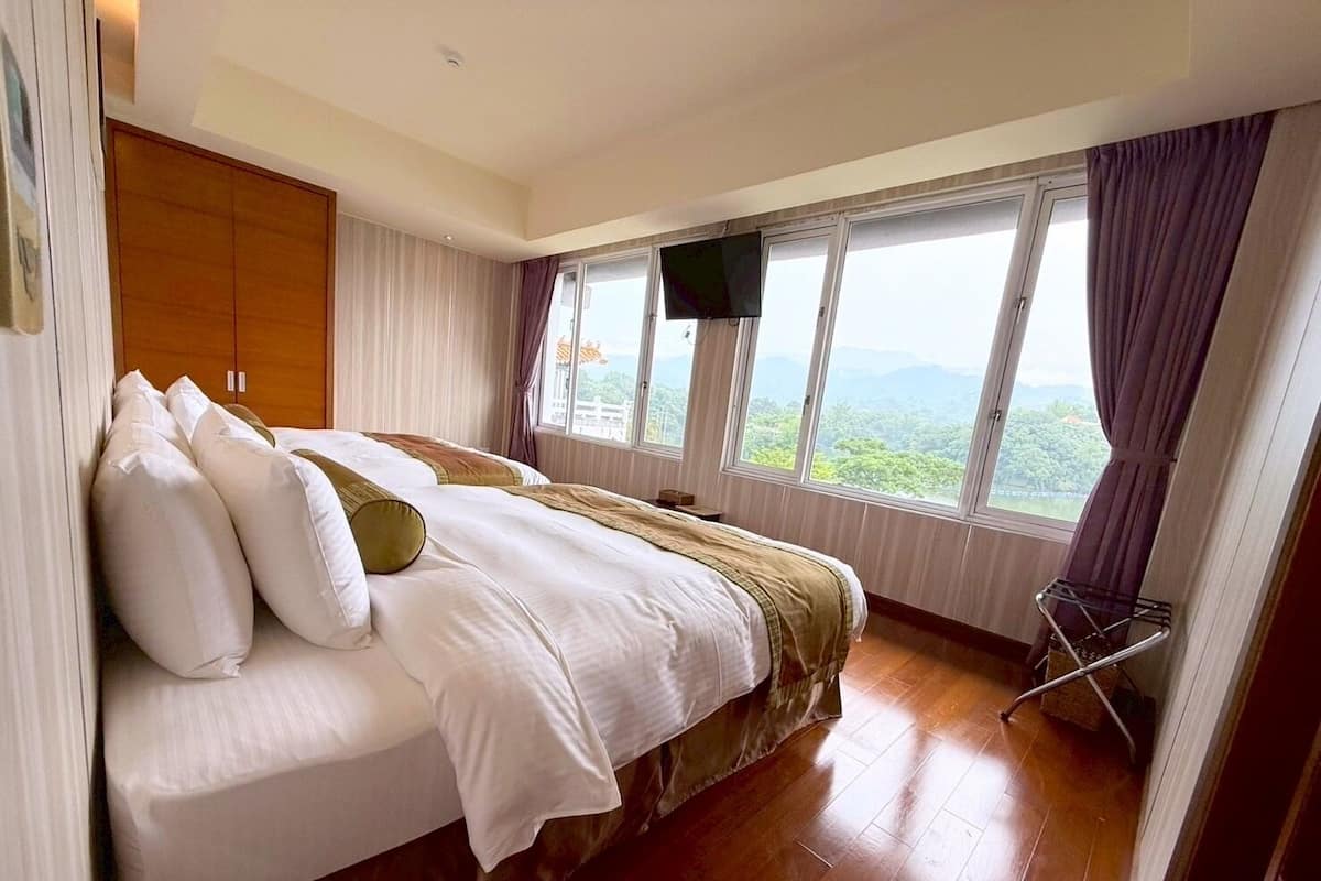 Un dormitorio con una cama grande, un armario de madera y una ventana con vistas a zonas verdes.