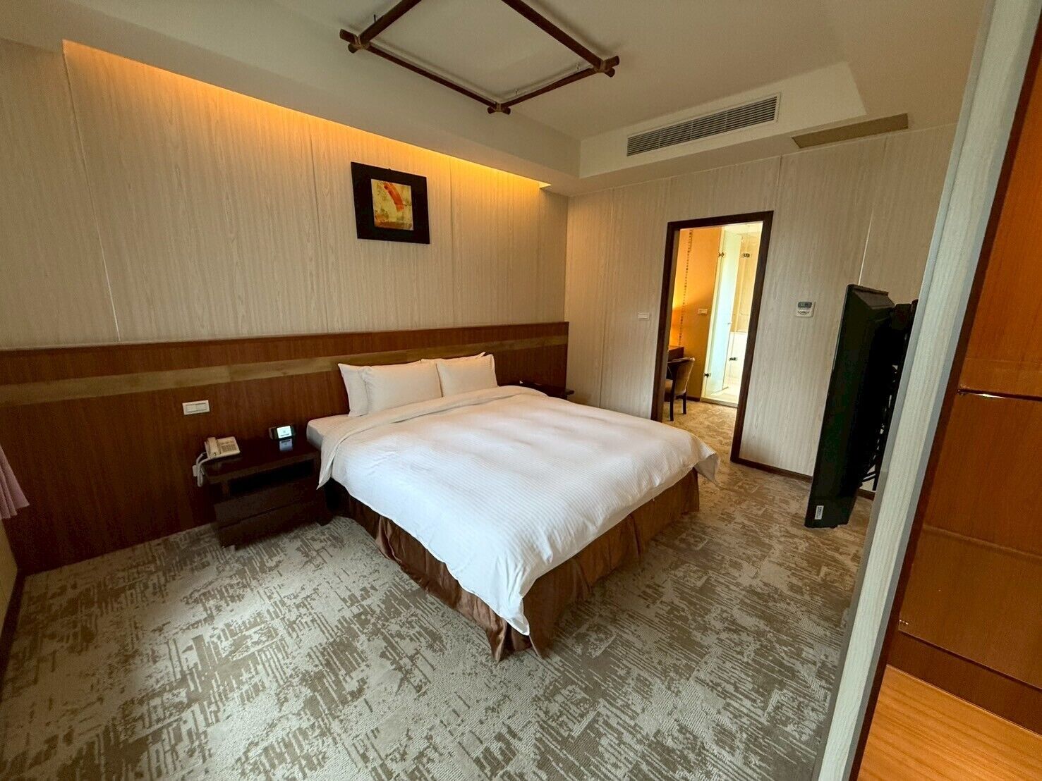 A hotel room with a large bed, a bedside table, a chair, and a television.