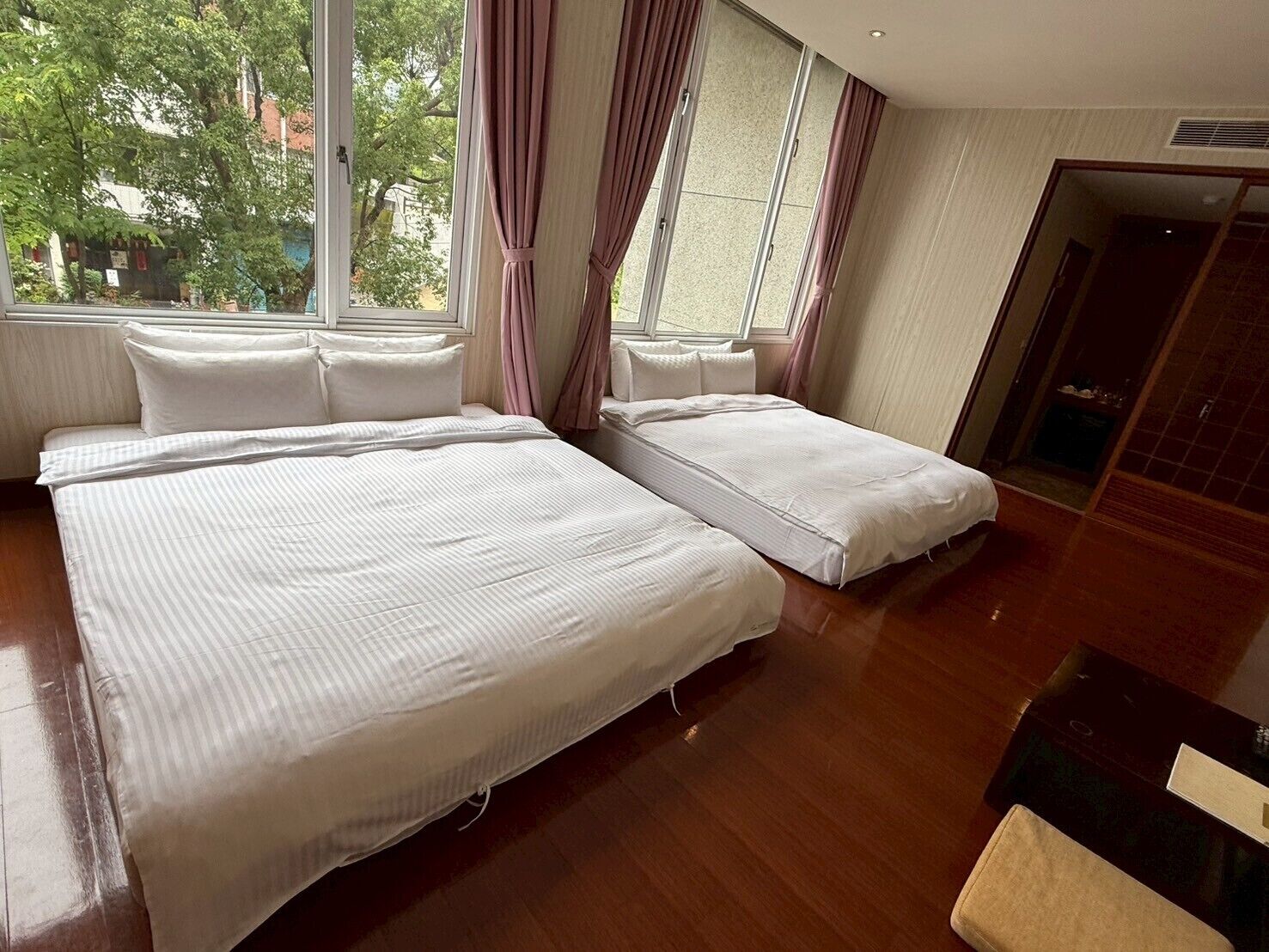 Hotellihuone, jossa on suuri sänky, kaksi yöpöytää ja ikkuna, jossa on verhot.