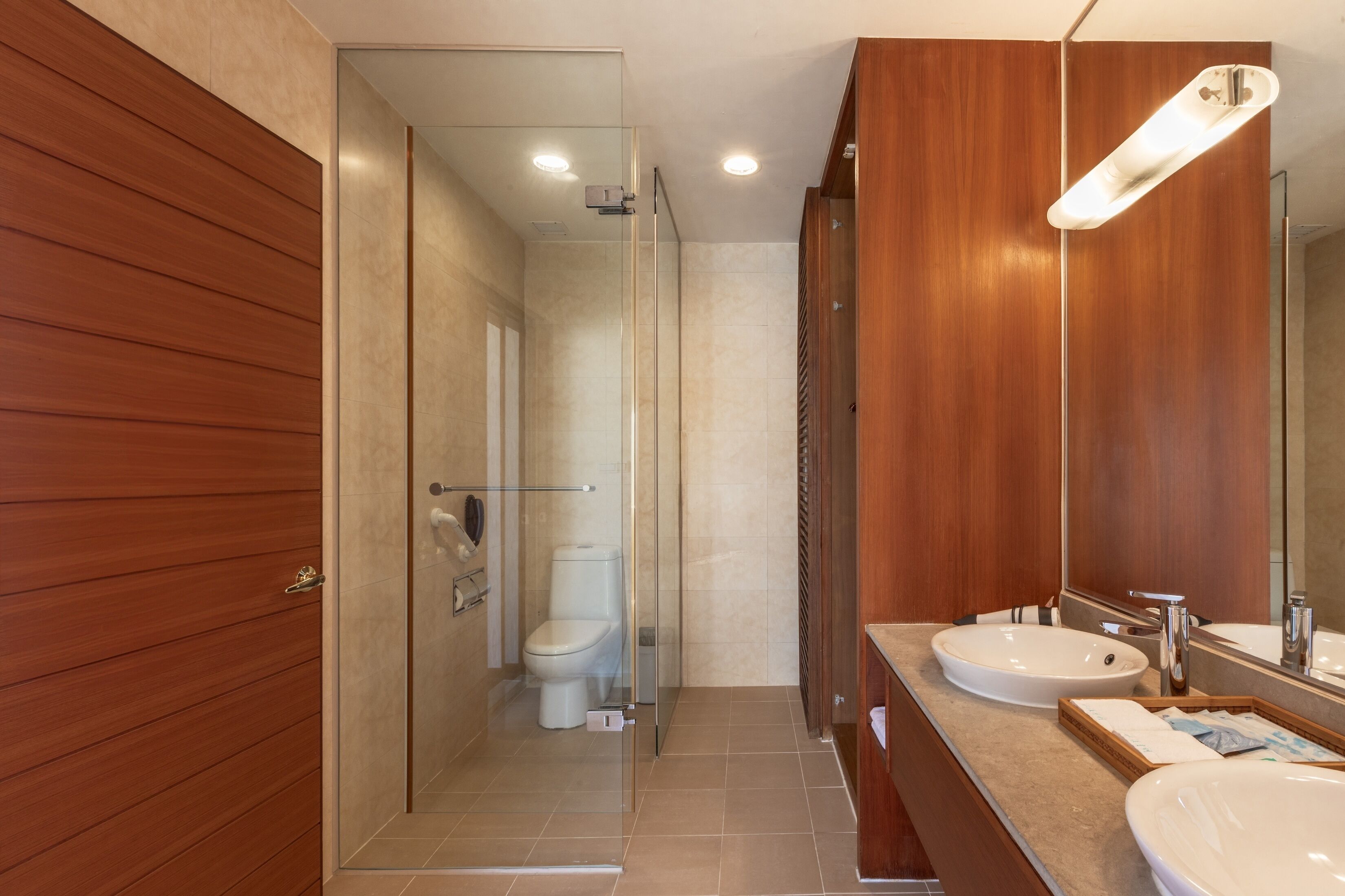 A modern bathroom with a glass-enclosed shower, a white toilet, and two sinks with mirrors.
