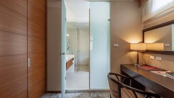 Un baño moderno con cabina de ducha de vidrio, tocador de madera y un escritorio con lámpara.