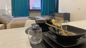 A hotel room with a bed, a desk with a glass, a bowl, a spoon, and a fork. - Les Trois Merveilles Green Fernando (Cesena)