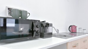 A kitchen with a microwave, coffee maker, and kettle on a white countertop. - Les Trois Merveilles Green Fernando (Cesena)